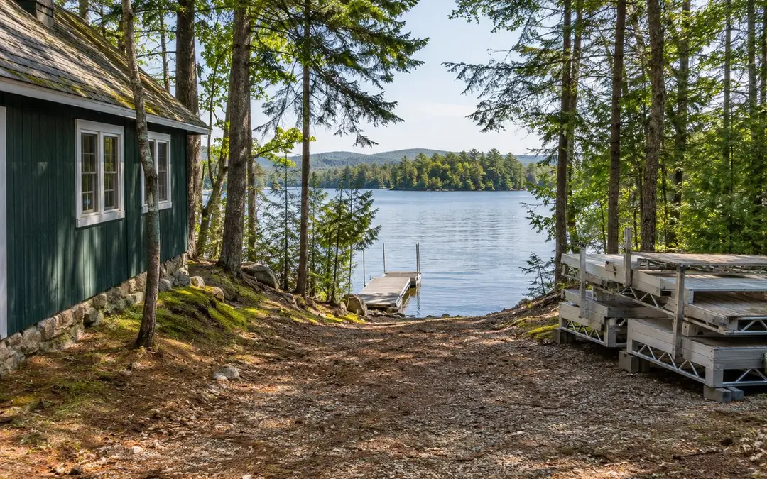 Illustrative camp beside trees and water with an open ground area
